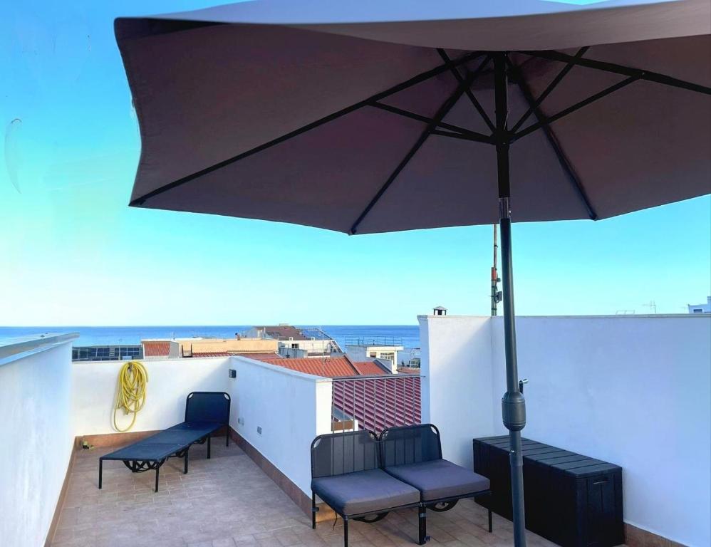 a patio with two chairs and an umbrella on a roof at La Terrazza Bella Sicula in Furci Siculo
