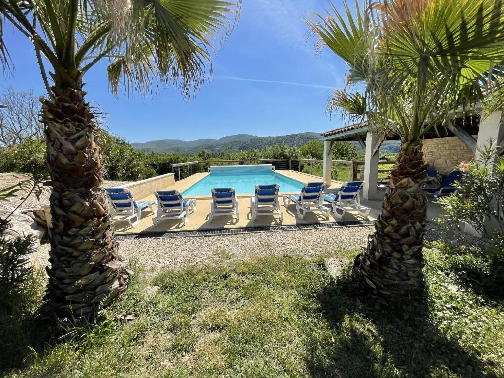 a pool with chaise lounge chairs and palm trees at Villa Vallon Pont d'Arc in Vallon-Pont-dʼArc