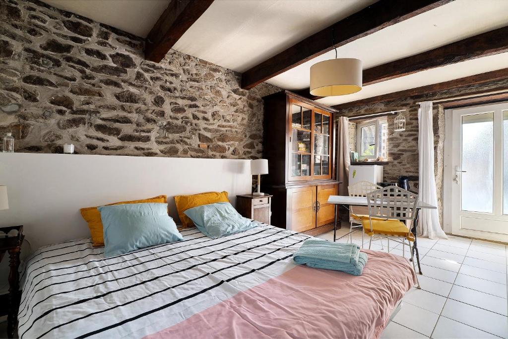 a bedroom with a bed and a stone wall at Chambre de garel in Le Minihic-sur-Rance