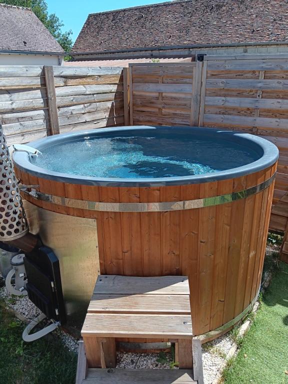 a hot tub in a backyard with a wooden fence at Le BENEZE entre Beauce et Perche in Saint-Hilaire-sur-Yerre