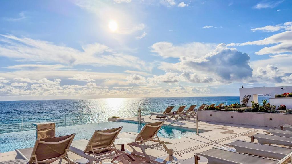 a pool with chairs and the ocean in the background at Perla Marina in Nerja