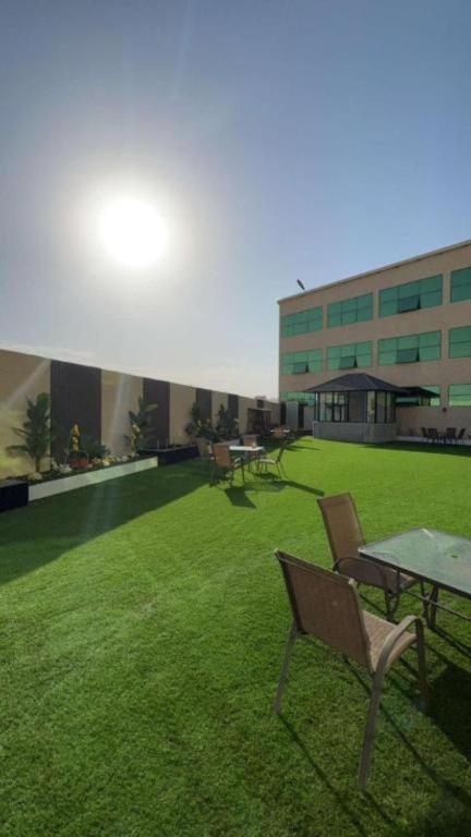 a lawn with tables and chairs and a building at شقق اجنحة تارا in Khamis Mushayt
