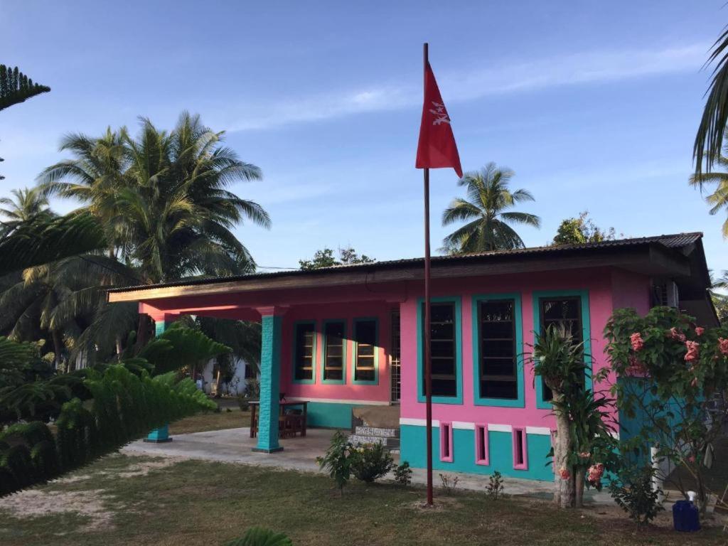 a pink and blue house with a flag at Seri Pengkalan Holiday House in Bachok