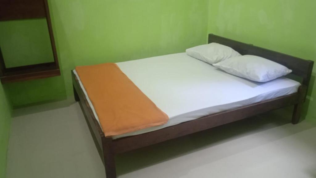 a bed with white sheets and pillows in a room at Oasis Homestay in Mendut