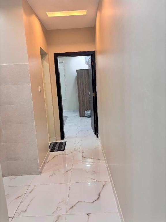 a hallway with white marble floors and a door at ايراد للشقق - النور in Dammam