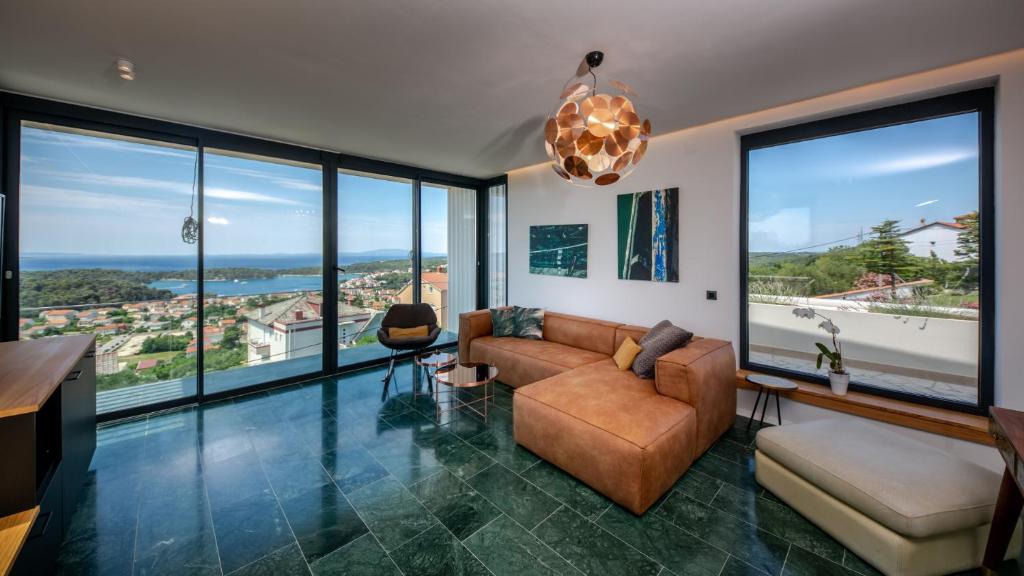 a living room with a couch and large windows at Luxury villa Mar with infinity pool in Rab in Palit