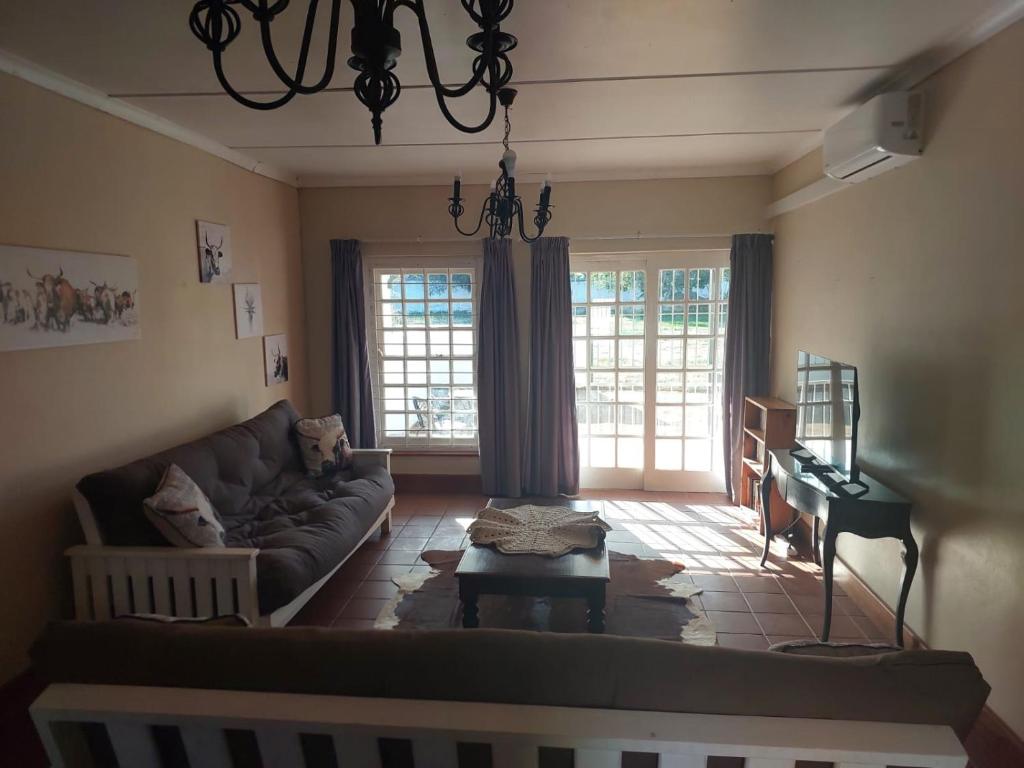 a living room with a couch and a piano at Nguni Cottage in Graaff-Reinet