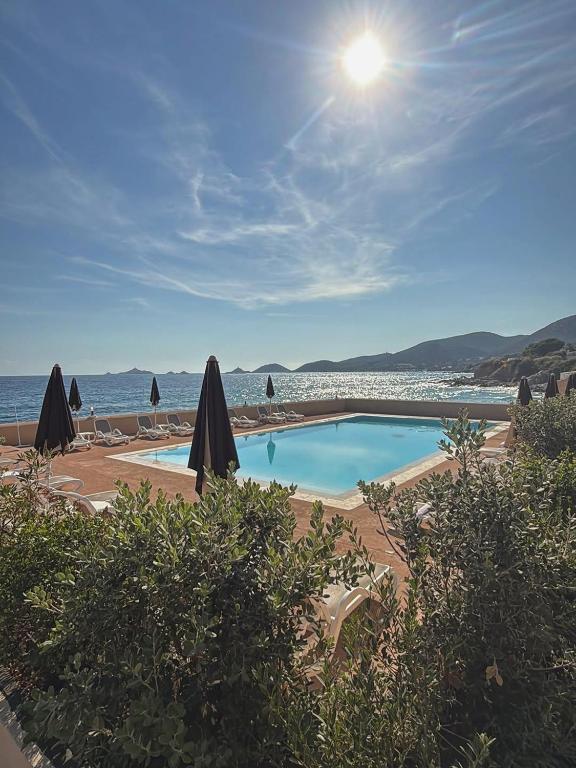 a swimming pool with umbrellas and the ocean at Hotel Stella Di Mare in Ajaccio