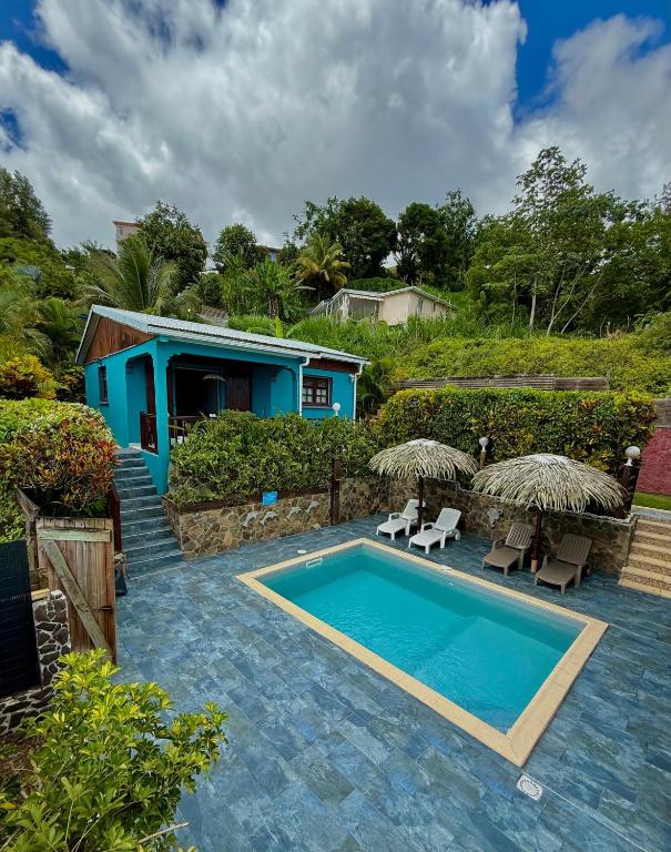 a swimming pool with two chairs and a house at LES VILLAS PAMEYAQUE 2 F2 avec 1 piscine, 1 F3 avec 1 piscine privée, Superbe Vue Mer in Rivière-Salée