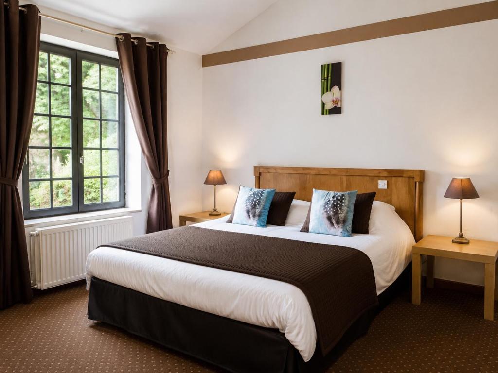 a bedroom with a large bed and two windows at Hotel du Golf de Clécy in Clécy