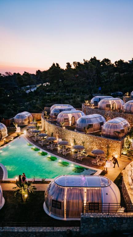 a resort with a pool with umbrellas and chairs at Piccolo Paradiso - Glamping Resort in Shëngjin