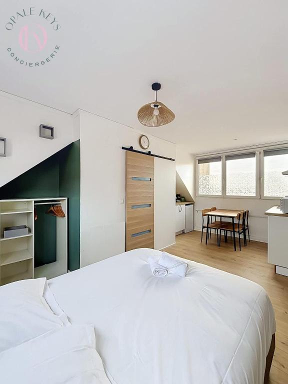 a bedroom with a large white bed and a table at Le Studio Bleu - Dernier etage & Confort in Coudekerque-Branche