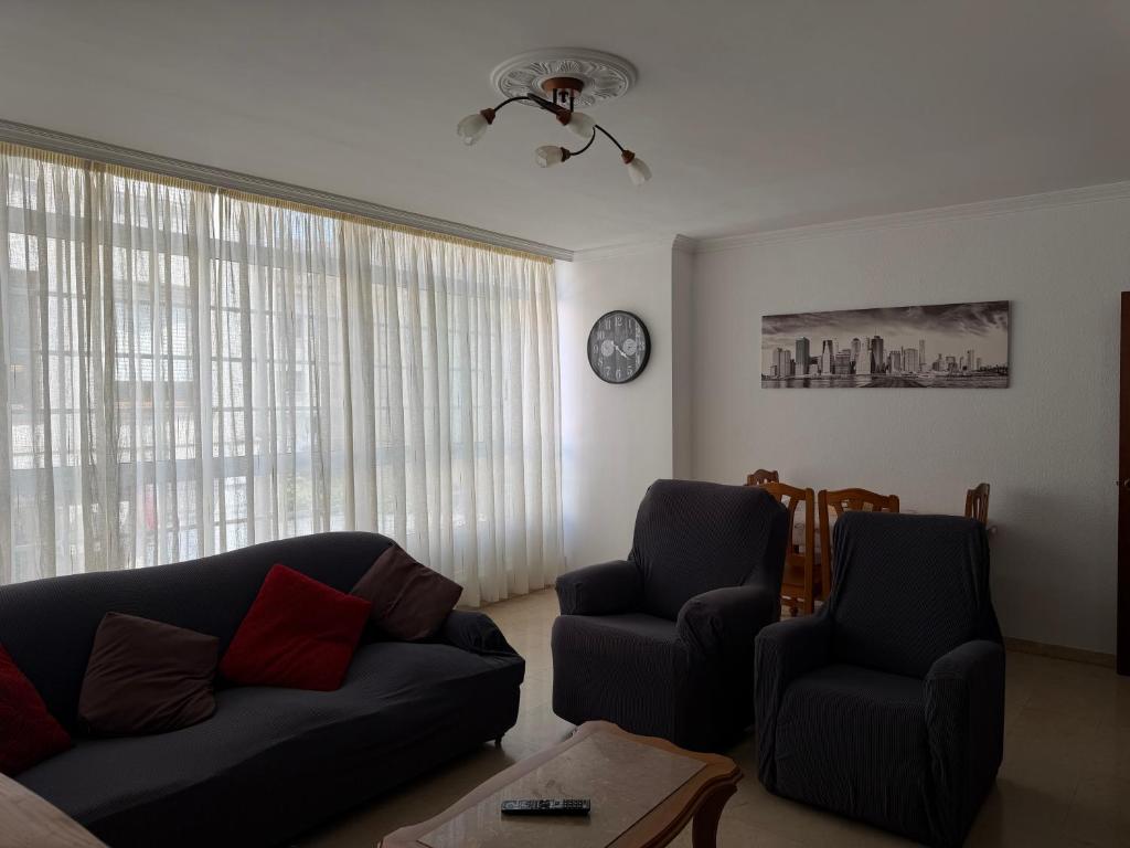 a living room with a couch and two chairs and a clock at Piso Super Espacioso en Cambados Centro in Cambados