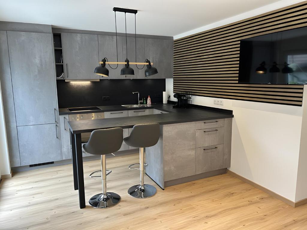 a kitchen with a black counter and two stools at Moderne Studio Oase in Donaueschingen