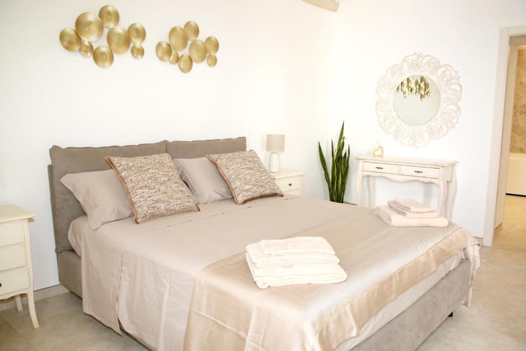 a white bedroom with a bed with towels on it at Antica Stella in Specchia