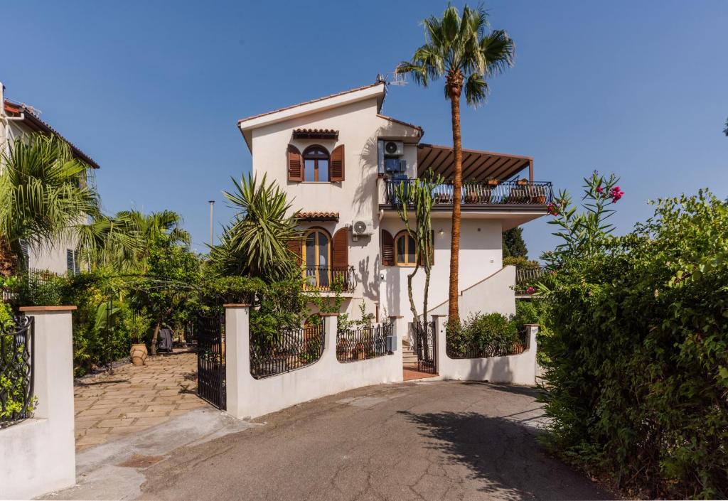 a white house with a gate and a palm tree at Villa Domina by Letstay in Giardini Naxos