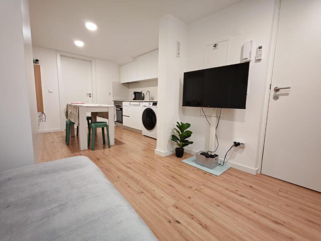 a white living room with a television on the wall at Apartamento com charme no centro histórico - Escura 36 in Viseu