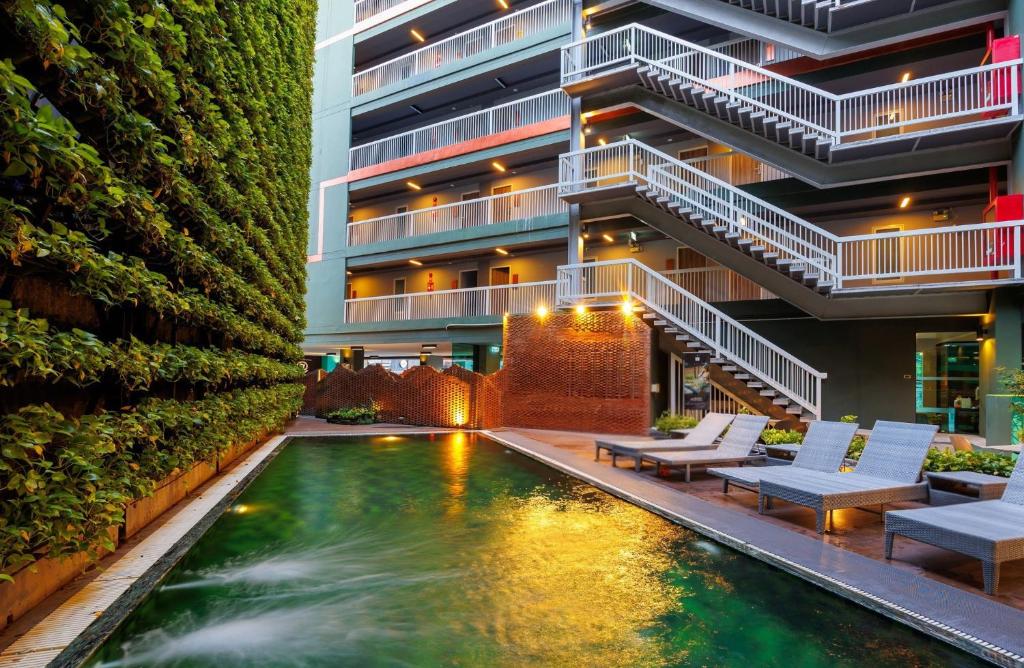 a hotel with a swimming pool in front of a building at Cross Vibe Chiang Mai Decem, Nimman in Chiang Mai