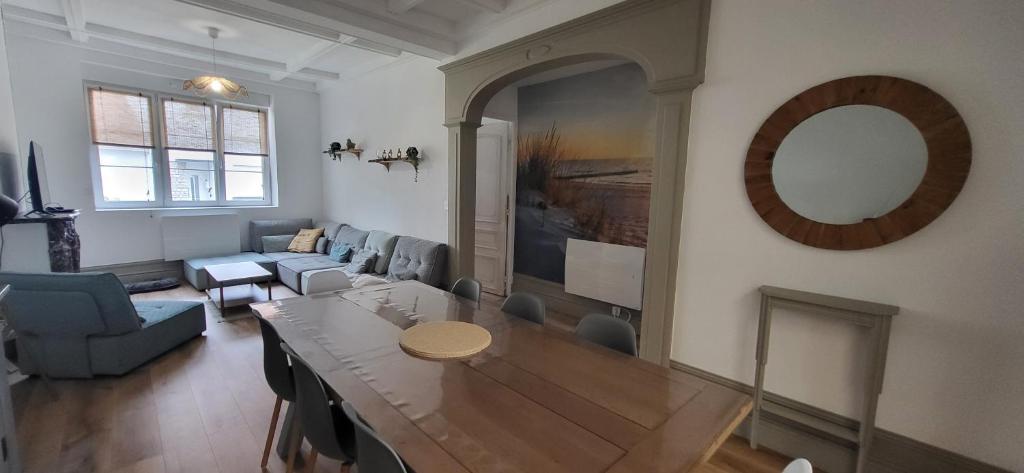 a living room with a table and a mirror at Le Cocon des Sables in Sangatte