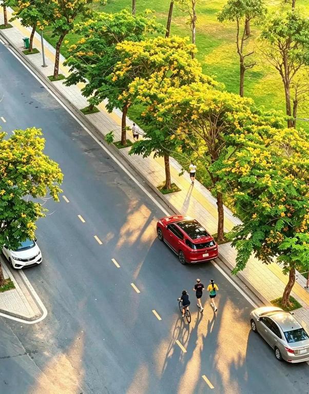 two people riding bikes down a street with a red car at Marina vinhomes in Long Bình