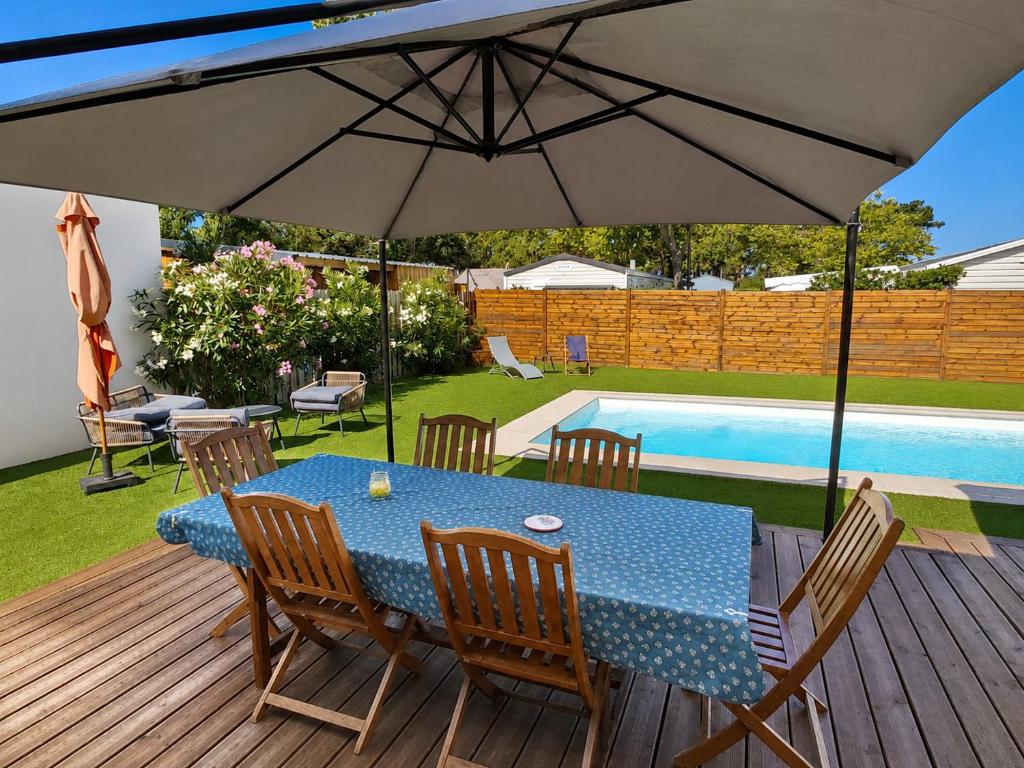 a table with an umbrella on a deck next to a pool at Le Havre des Dunes in Brem-sur-Mer
