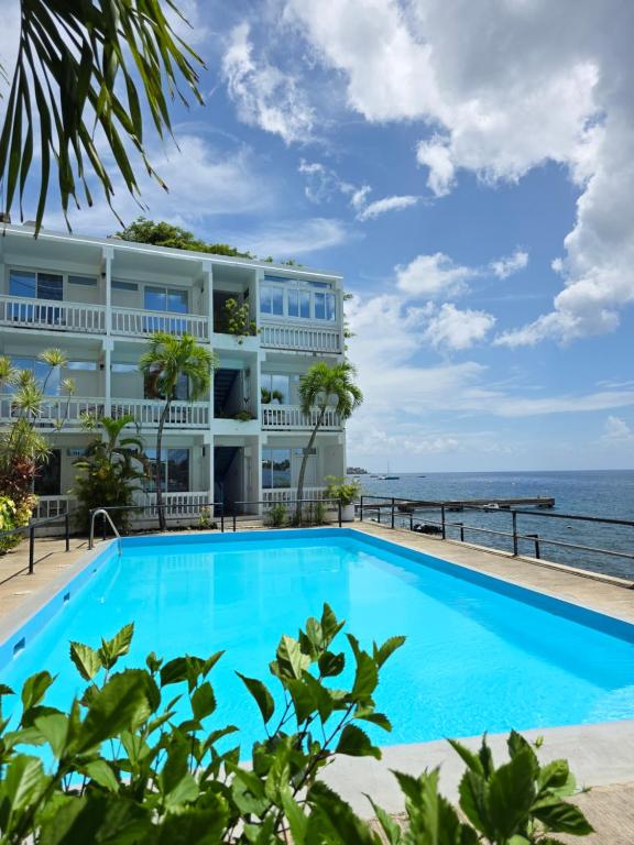 a swimming pool in front of a building with the ocean at OE at Anchorage Hotel in Roseau