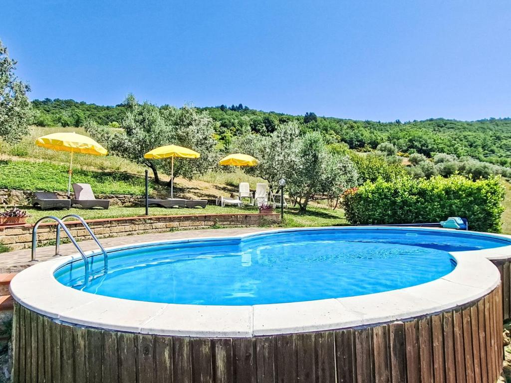a large swimming pool in a yard with umbrellas at Holiday Home Luce by Interhome in Dicomano