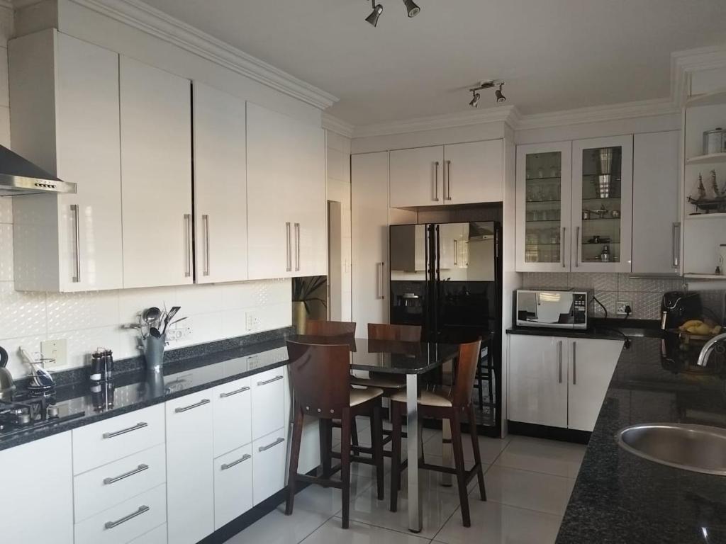 a kitchen with white cabinets and a table and chairs at Stay & unwind in Alberton