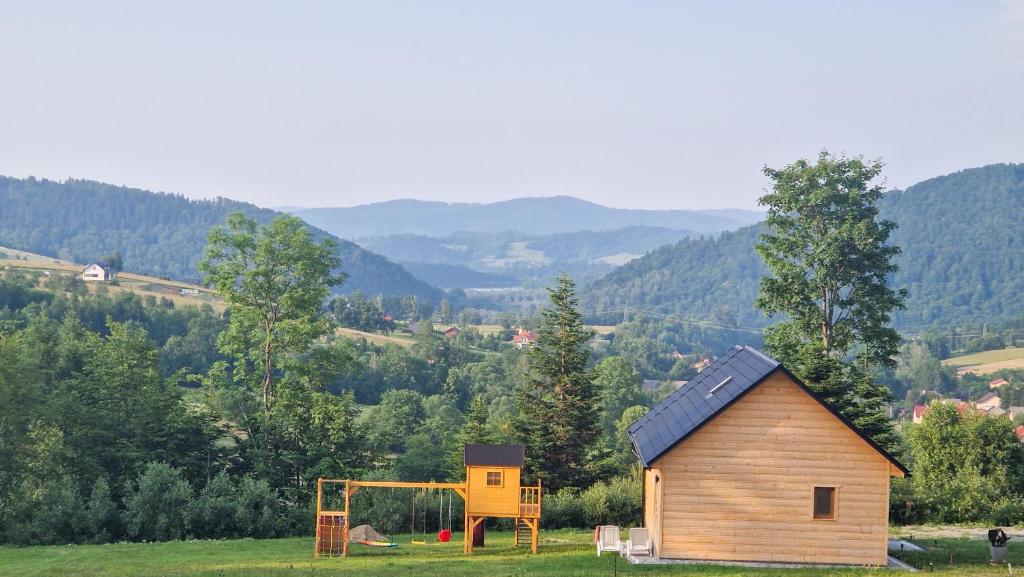 a small house and a playground in a field at Fraseryja domek w Bieszczadach in Bukowiec