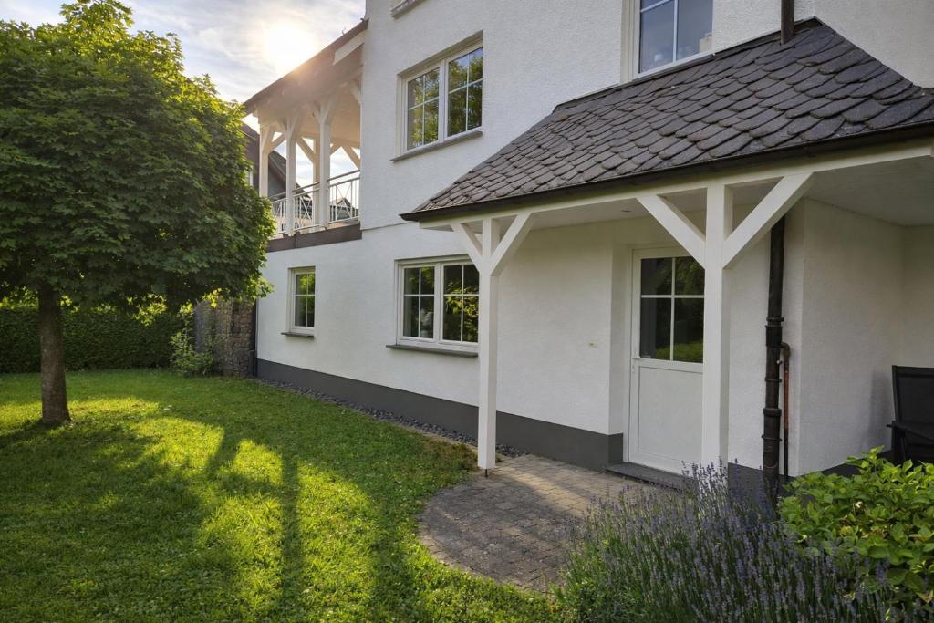 a white house with a white door and a yard at Ferienwohnung Talblick in Schmallenberg