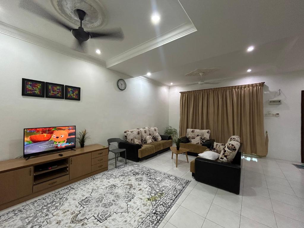 a living room with couches and a flat screen tv at Fairuz Homestay Ipoh in Ipoh