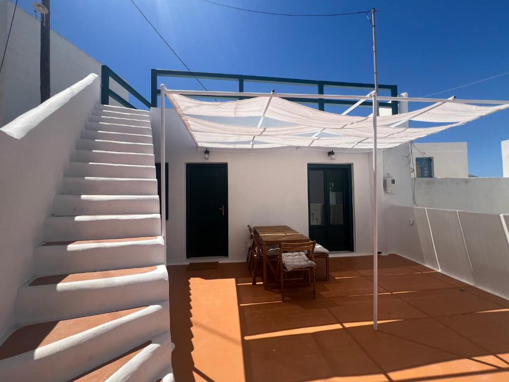 a white staircase with a table and a white canopy at Iconic Project Lagada in Amorgos