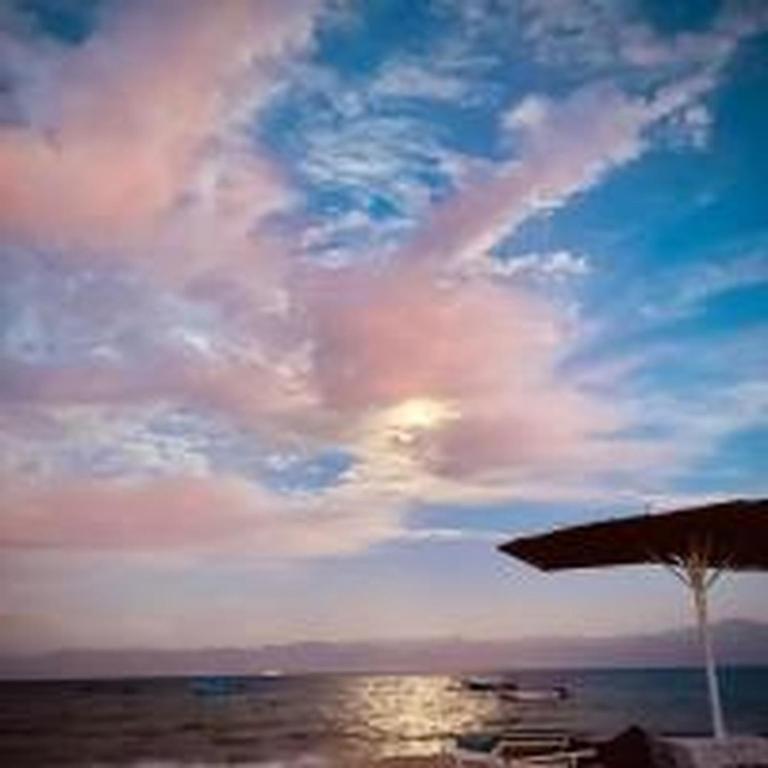 a beach with an umbrella and chairs and the ocean at elwaharesort in Wāsiţ