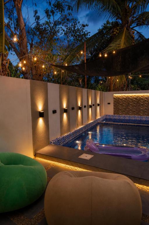 a pool at night with a green chair and lights at K&M Studio Suites Casa KM in Bingag