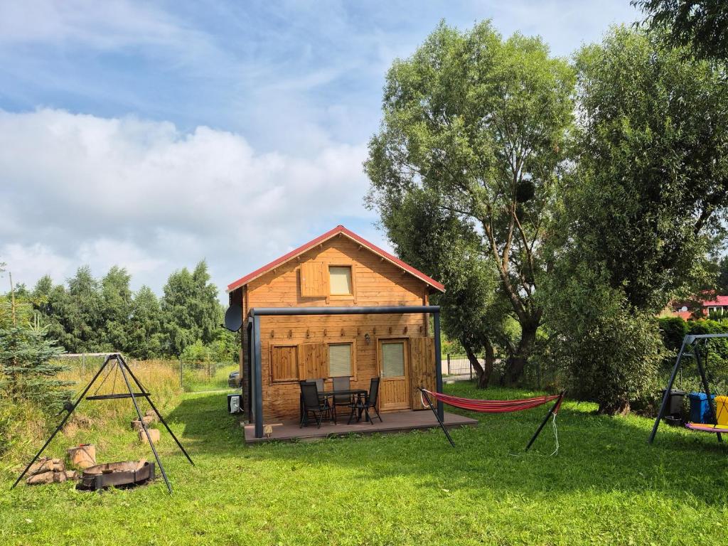 a tiny house with a hammock in the yard at Domek pod Wierzbami in Leleszki