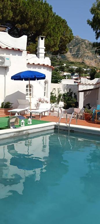 a large swimming pool with a blue umbrella and chairs at Villa Aida Luxury Apartments & Spa in Forio d'Ischia