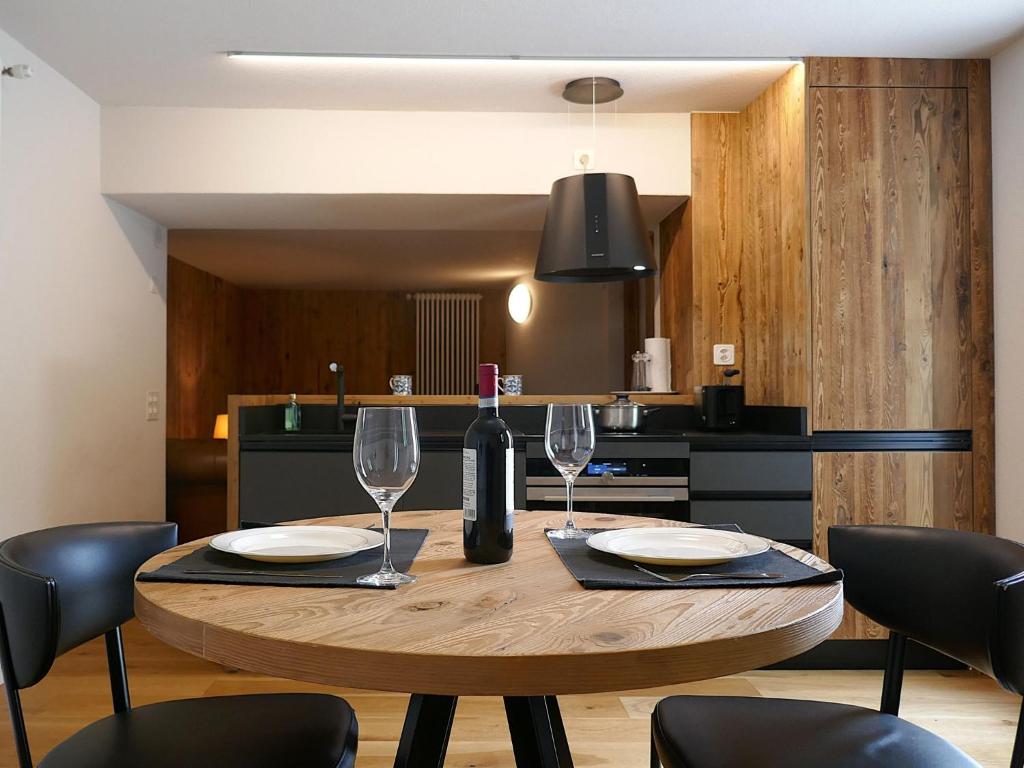 a table with a bottle of wine and two glasses at Apartment Rina by Interhome in Olivone