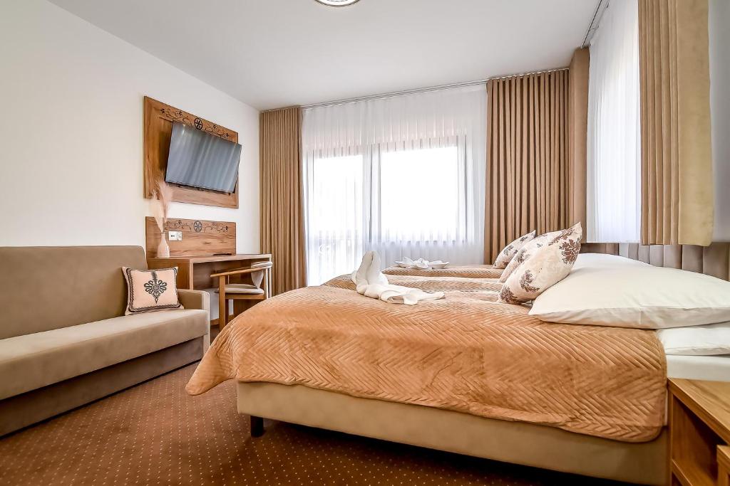 a bedroom with a bed and a couch and a window at Cichowiański Folk & Prestige in Poronin