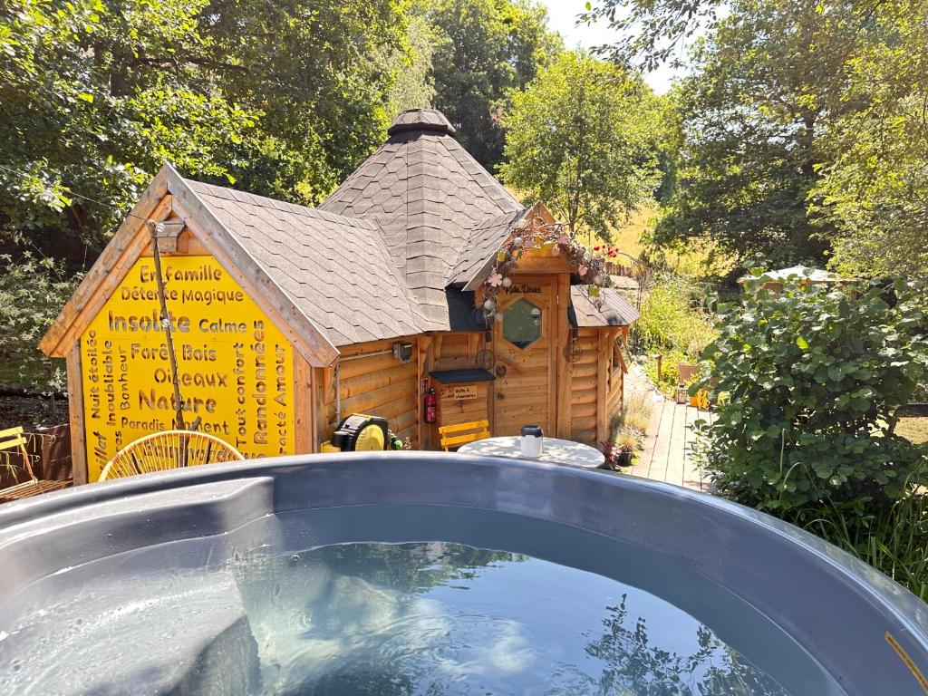 a house with a roof in front of a pool at Cabane Kota Désiré, bain nordique in Saint Die