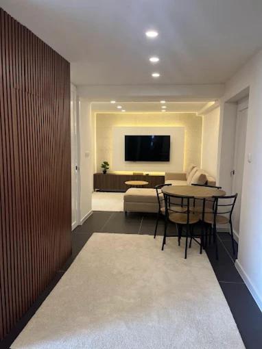a living room with a table and a television on a wall at Apartman Kvesić in Široki Brijeg