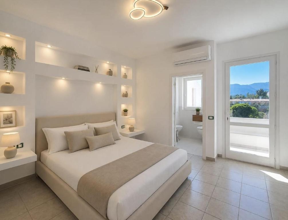 a white bedroom with a large bed and a bathroom at Hotel Cala d'Oro - Hotel a pochi minuti dal mare di Cala Liberotto in Cala Liberotto