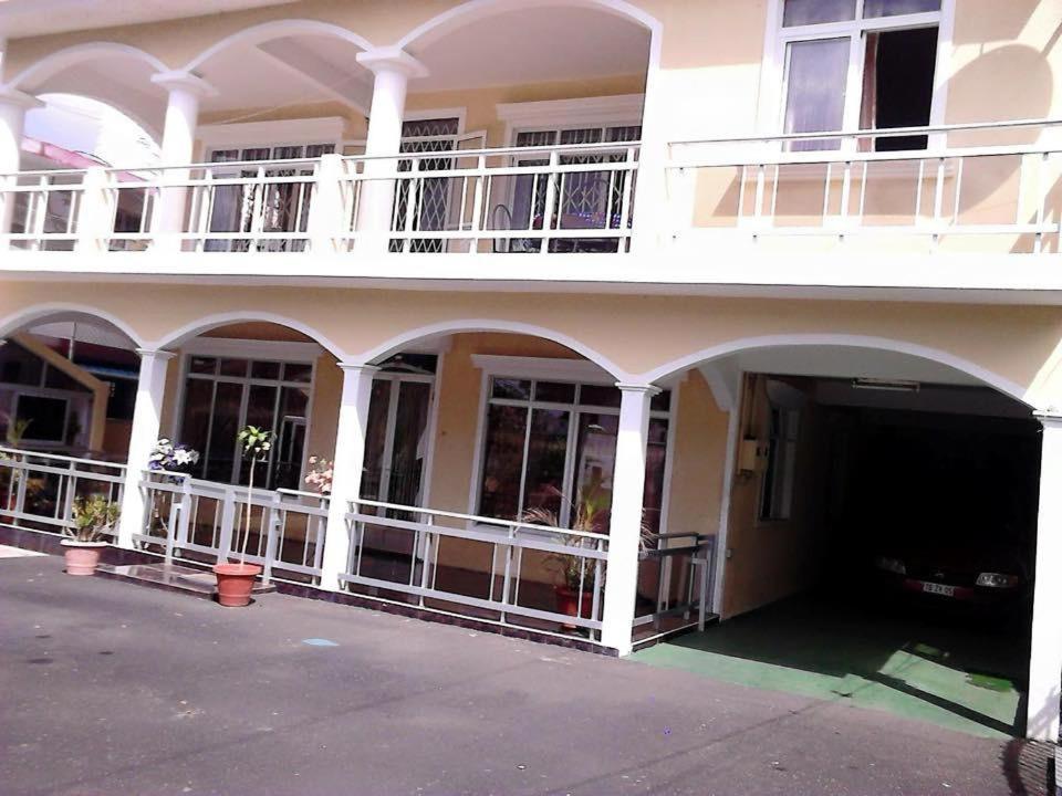 a large white building with balconies and a courtyard at Shivram guest house in Plaine Magnien