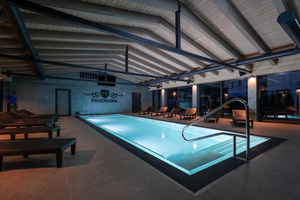 a swimming pool in a building with tables and chairs at Penzion Panorama - Celoročný krytý bazén v cene in Liptovský Mikuláš