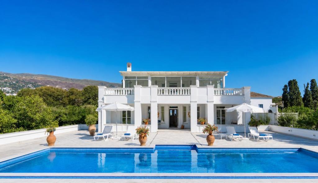 a large white house with a swimming pool at Villa Cypress with Private Pool and Mountain Views in Andros