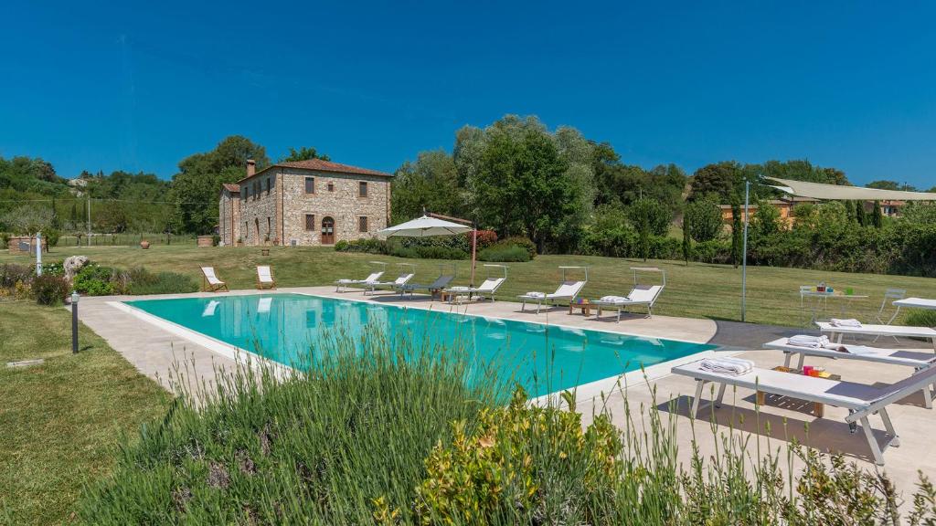a swimming pool with chairs and a building in the background at ALBORATA 10, Emma Villas in San Giovanni dʼAsso