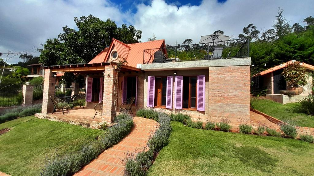a brick house with purple shutters on a yard at Cabaña Las Lavandas in Samaipata
