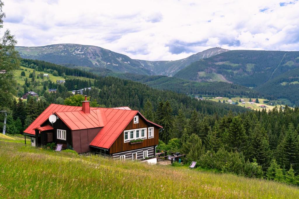 a barn on a hill with mountains in the background at Pension Skalicky in Pec pod Sněžkou