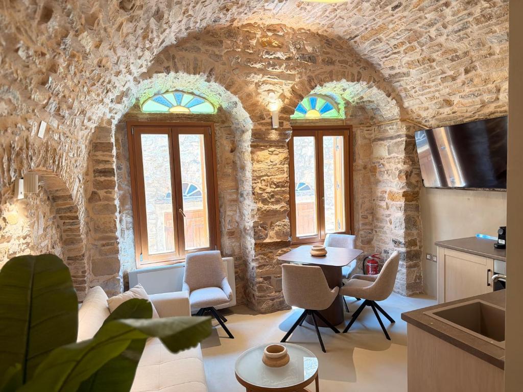 a kitchen with a living room with stone walls and windows at Opus Luxury Maisonette in Chios