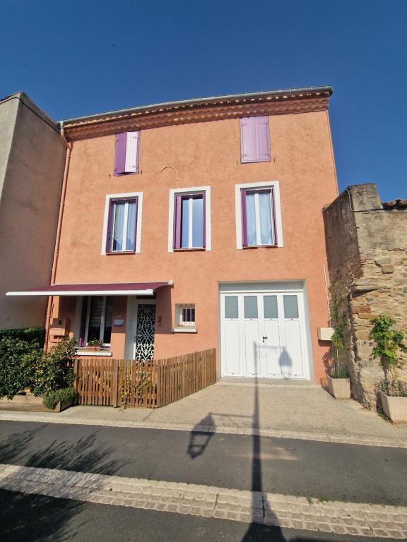 a large brick house with a white garage at L'escapade colorée anciennement La Vieille Forge in Rieux-Minervois