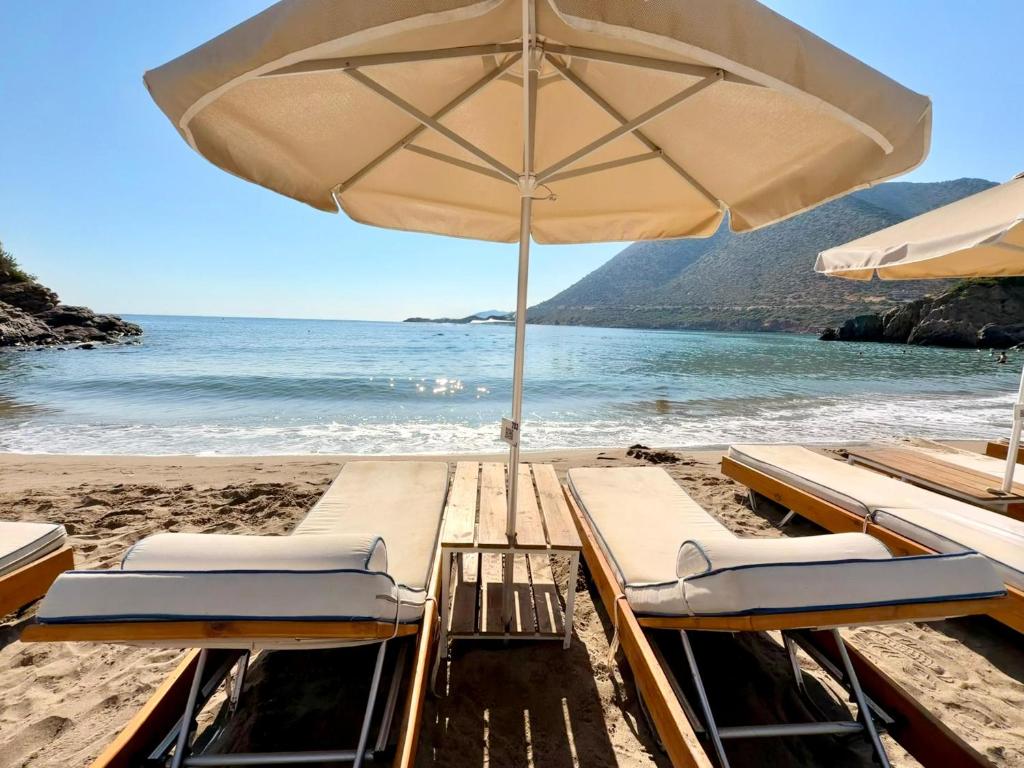 a beach with lounge chairs and an umbrella at Bali Bay Villa in Bali